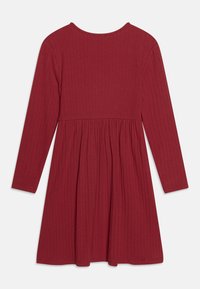 Rippiges langärmliges Kleid in Dunkelrot mit rundem Ausschnitt, tailliertem Oberteil und schwingendem, gerafftem Rock. Glatte Textur im gesamten Kleid.
