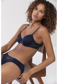 Navy blue lingerie set, joka sisältää pehmustetun rintaliivin, jossa on pitsireunus, ja yhteensopivat alushousut, molemmat valmistettu sileästä kankaasta hienoilla yksityiskohdilla.