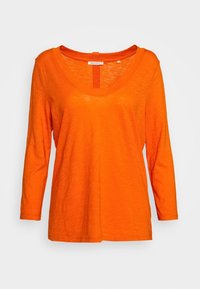 T-shirt arancione a maniche lunghe realizzato in un morbido tessuto testurizzato. Presenta un colletto scozzese e un design a vestibilità morbida. Etichetta visibile al collo.