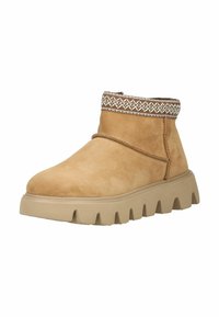 Bottines en suede tan avec un revers texturé brun et blanc, un bout arrondi et une semelle épaisse et crantée.