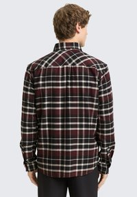 Koszula z długim rękawem w czarno-czerwono-biały wzór w kratę. Posiada kołnierzyk w szpic i zapinane na guziki mankiety, wykonana z miękkiego materiału.