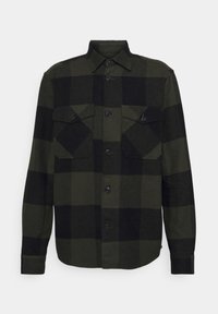 Camisa de franela de cuadros verdes y negros, con cierre de botones en el frente, cuello amplio y dos bolsillos en el pecho con solapas.