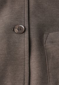 Chemise marron à boutons avec un tissu texturé, dotée d'un bouton rond, de coutures piquées et d'un détail de poche poitrine.