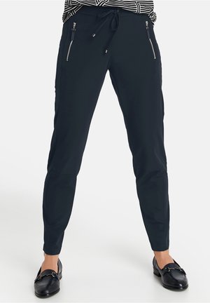 Sorte slimfitbukser med snøre i taljen og lynlåslommer i siden båret med sorte loafers og en stribet top.
