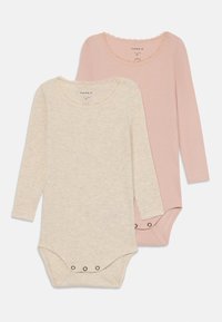 To langermede bodyer i beige og lys rosa bomull. Med bølgete halsutringning og knapper nederst. Mykt, strukturert stoff.