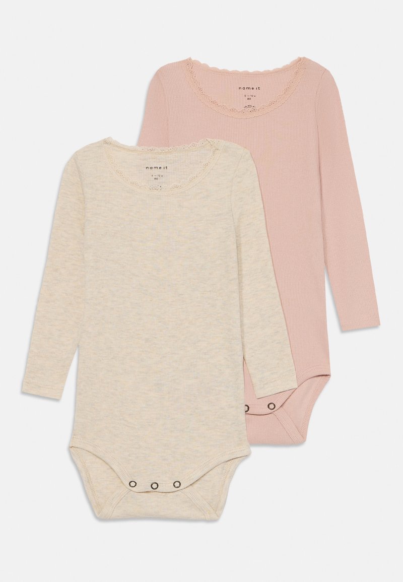 Du kišeninių ilgomis rankovėmis bodžiai, nudažyti smėlio spalvos ir šviesiai rožinės medvilnės. Jų apykaklė yra banguota, o apačioje yra snapelių uždarymas. Minkšta, tekstūruota medžiaga.