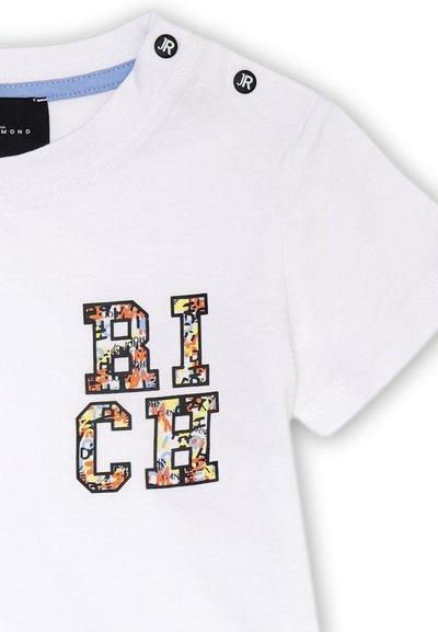 T-shirt bianco in cotone a maniche corte con grafica "RICH" in un motivo colorato. Presenta bottoni neri sulla spalla e una rifinitura blu sul collo.
