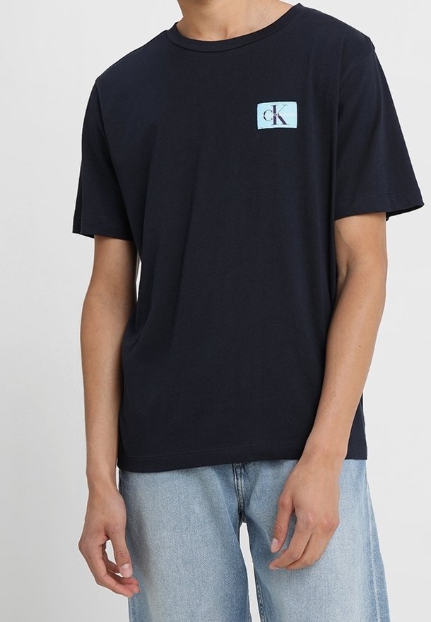 Mörkblå bomulls T-shirt med kort ärm, prydd med en ljusblå CK-logotyp på vänster bröst. Avslappnad passform och mjuk textur.