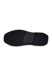 Semelle de chaussure noire avec un design en caoutchouc texturé, présentant des rainures parallèles et une zone centrale lisse. Accent légèrement surélevé près du talon.