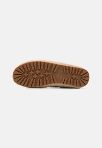 Semelle d'une chaussure avec des motifs de semelle profonds et de petites formes en croix, semelle extérieure en caoutchouc marron clair sur une semelle intercalaire tissée.