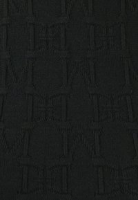 Čierny textil s opakujúcim sa vzorom prepletených písmen, s jemnou textúrou a leskom, ktoré zvýrazňujú detaily dizajnu.