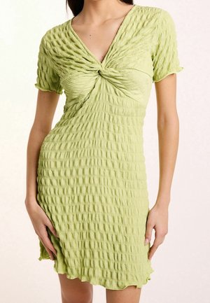 Lichtgroene jurk met een gestructureerde, gerimpelde stof. V-hals en een gedraaide detail aan de voorkant. Korte mouwen en een geschulpte zoom.