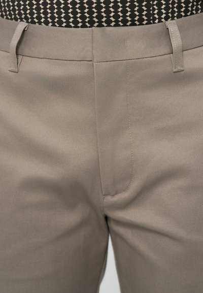 Ανοιχτό γκρι παντελόνι από ύφασμα με λεία υφή. Διαθέτει μπροστινές τσέπες και θηλιές για ζώνη, με διακριτική γυαλάδα και εφαρμοστή γραμμή.