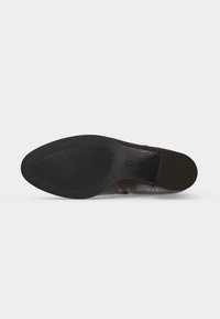 Semelle d'une chaussure de ville en cuir marron foncé avec une semelle en caoutchouc texturée et le nom de la marque "GAROR" estampillé près du talon.