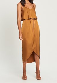 Satin midi-jurk in warm bruin, met spaghettibandjes, gelaagde bovenkant, geplooide rok en een diagonale zoom. Gladde textuur.