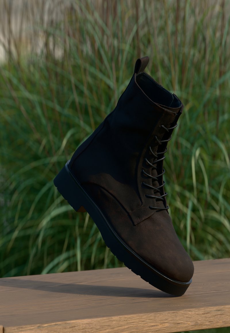 Bottine noire en cuir avec une semelle robuste, dotée d'un laçage à l'avant et d'une boucle au talon pour un enfilage facile. Détails de surface texturée.