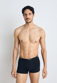 Boxeri negri dintr-un material moale, cu un design ajustat și o talie elastică, având branding alb "GANT".