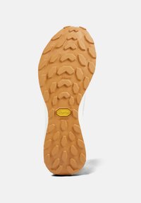 Rubberen buitenzool met multidirectionele noppen, in een lichtbruine kleur met Vibram-merken, biedt grip en duurzaamheid voor verschillende terreinen.