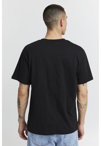 Black cotton t-shirt with a relaxed fit, short sleeves, and a rounded neckline, featuring a back seam detail.