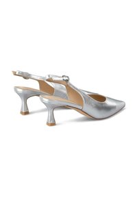 Zapatos slingback metálicos plateados con puntas afiladas, un tacón redondeado y una correa con un accesorio de hebilla circular. Textura suave.