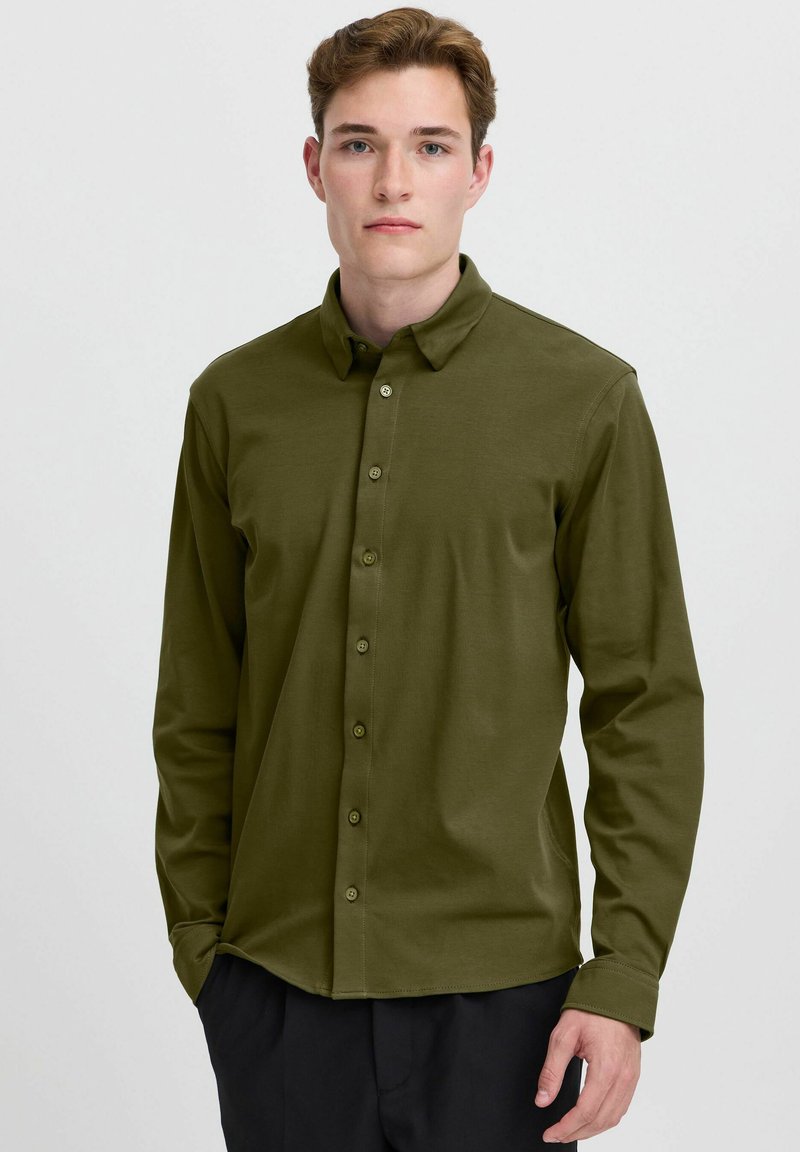 Long-sleeve, olive green button-up shirt made of smooth fabric with a collar, featuring a front button closure and buttoned cuffs.