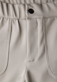 Ljust grå tygbyxor med en slät yta, elastisk midja, veckad front och svart knappdetalj.