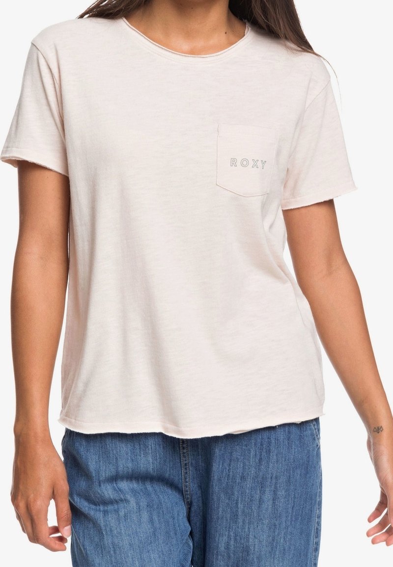 Světle růžové tričko s krátkým rukávem vyrobené z měkké látky, s náprsní kapsou, na které je jednoduchým písmem logo "ROXY". Uvolněný střih.