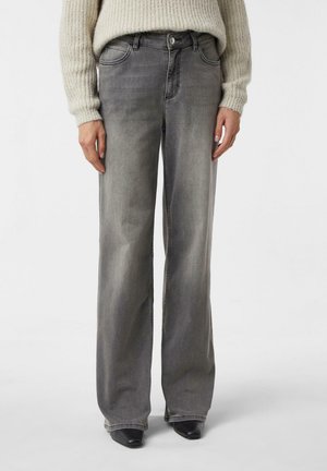 Szare dżinsy o szerokich nogawkach z delikatnym efektem sprania, klasycznym pięciokieszeniowym fasonem, metalowym guzikiem i szlufkami na pasek, zestawione z teksturowanym swetrem z dzianiny.