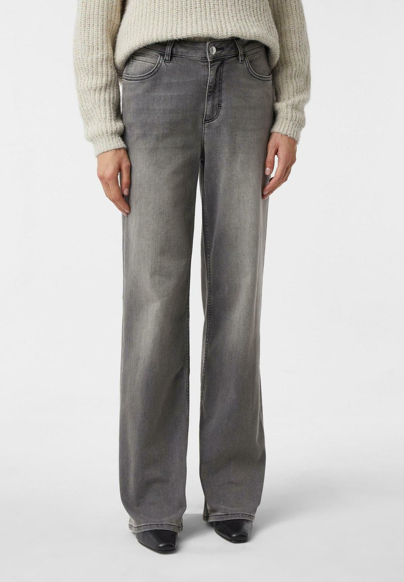 Szare dżinsy o szerokich nogawkach z delikatnym efektem sprania, klasycznym pięciokieszeniowym fasonem, metalowym guzikiem i szlufkami na pasek, zestawione z teksturowanym swetrem z dzianiny.