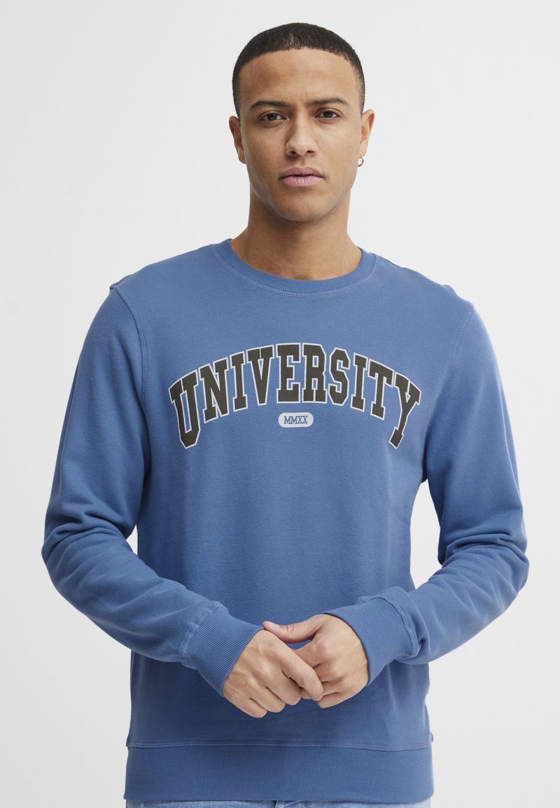 Sudadera azul con puños y cuello de canalé, con "UNIVERSITY" en letras negras en negrita cruzando el pecho. Material suave con un corte relajado.