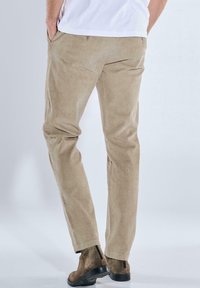 Beige Corduroyhosen mit geradem Bein, strukturiertem Stoff und Seitentaschen, kombiniert mit braunen Wildleder-Stiefeletten.