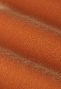 Tissu texturé de couleur orange chaude, présentant une surface douce et lisse avec un léger éclat et des fibres fines, plié pour révéler une apparence stratifiée.