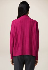 Cardigan côtelé magenta avec un col montant, une coupe décontractée et des manches larges. Texture tricotée, avec une finition lisse à l'ourlet.