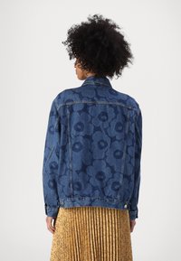 Jeans jakna s temnim cvetličnim vzorcem, dvema stranskima žepe, in zapenjalo na manšetah. Ima klasičen ovratnik in sproščen kroj.