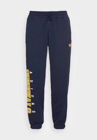 Pantaloni della tuta blu navy con vestibilità comoda, dotati di una vita elastica, polsini elasticizzati e scritta del marchio gialla lungo il lato sinistro.
