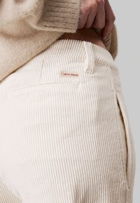 Crèmekleurige corduroy broek met een ribbelstructuur, voorzien van een klein Calvin Klein-logo label op de tailleband en zijzakken.