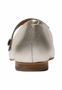 Zapato de cuero plateado metálico con punta redondeada, tacón pequeño y una correa decorativa con un botón negro en el lateral.