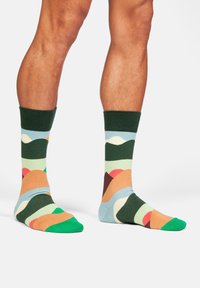 Gemusterte Socken mit einer Mischung aus grün, blau, orange und pink, einem weichen Textil und kontrastierenden gerippten Bündchen.