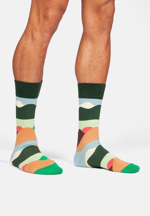 Gemusterte Socken mit einer Mischung aus grün, blau, orange und pink, einem weichen Textil und kontrastierenden gerippten Bündchen.