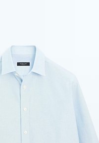 Jasnoniebieska koszula zapinana na guziki z klasycznym kołnierzykiem, delikatną teksturą i białymi guzikami. Metka zawiera napis "Massimo Dutti."