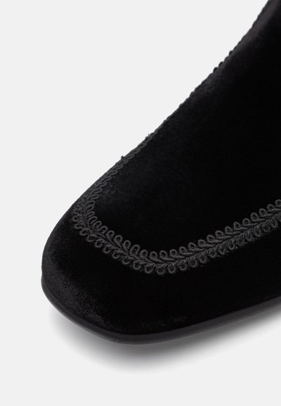 Pantof maiou negru din catifea, cu vârf rotunjit, cusături decorative pe margine și o textură netedă cu o ușoară strălucire.