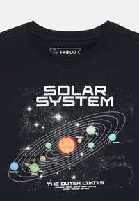Fekete póló, naprendszer grafikával, színes bolygókkal, ragyogó nappal és szöveggel. Pamut anyagból készült, kerek nyakú dizájn.