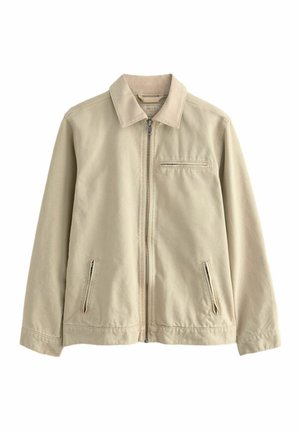 Giacca in cotone beige con colletto, zip frontale e due tasche laterali con zip. Include una piccola tasca sul petto con zip. Texture liscia.