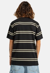 Camiseta negra de manga corta con rayas horizontales beige, hecha de algodón suave, con un corte relajado y escote redondo.