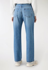 Jeans in denim azzurro chiaro con vestibilità comoda, gambe dritte e due tasche posteriori. Leggera scoloritura a formare pieghe e orlo sfrangiato.