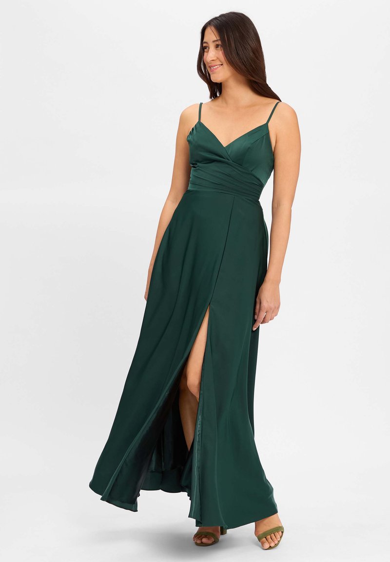 Robe longue verte avec des bretelles spaghetti, un décolleté en V et un design drapé. Comprend une fente haute sur la cuisse et un tissu lisse et fluide.