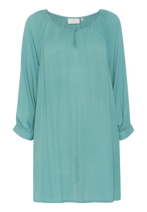 Teal színű, könnyű blúz hosszú, felgöngyölt ujjakkal és kerek nyakkivágással. Finom textúrával rendelkezik, és egyetlen gombos részlet található elöl.