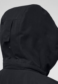Giacca nera con cappuccio caratterizzata da una finitura liscia e opaca e cuciture dettagliate. Include una toppa sul retro e un bottone a pressione per una vestibilità sicura.