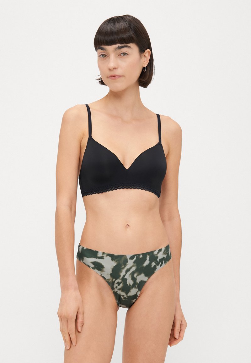 Czarny, pikowany biustonosz bralet z falbaniastym wykończeniem, w połączeniu z brązowo-zielonymi spodniami bikini w pasy tie-dye, z niskim stanem i gładką fakturą.