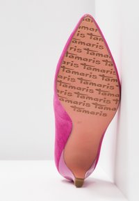 Chaussure à talon haut en daim rose pointue vue de la semelle avec motif texte "Tamaris" sur la semelle et indication de taille 37.